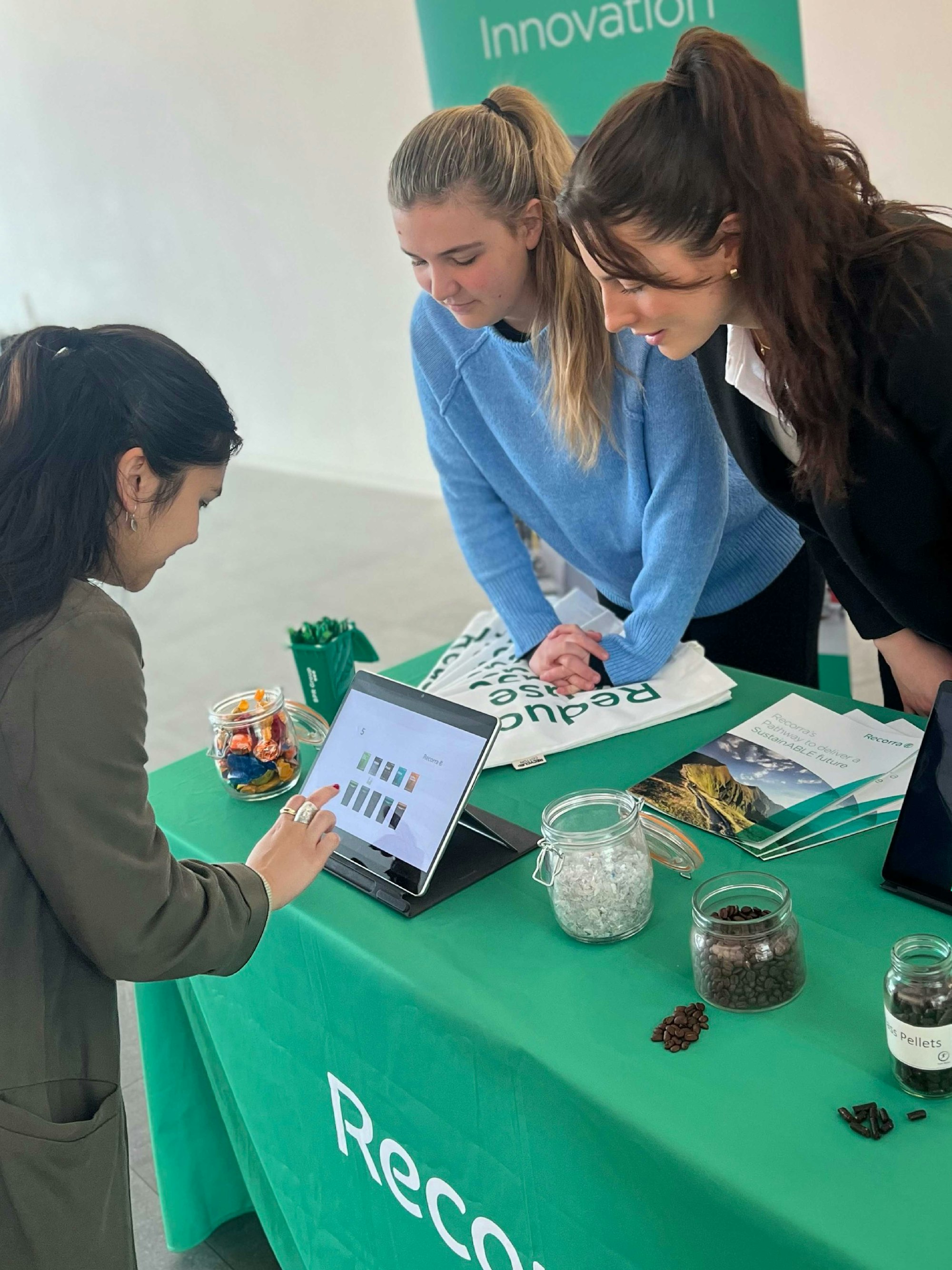 Awareness stand in the entrance of a Derwent London building. Emily Wilson-North (right), Hannah Shorter (middle) help a staff member in playing a game on touch screen tablet.