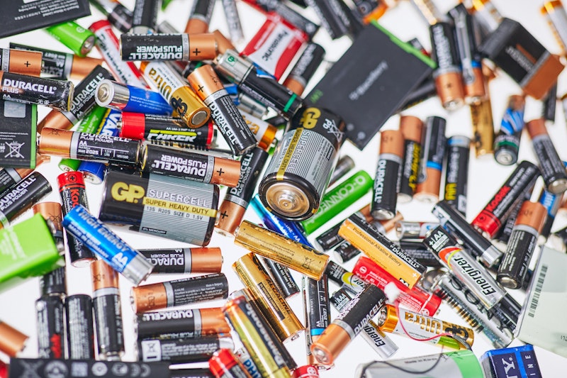 A variety of batteries cover a plain white background. Battery sizes differ from A to triple AAAs and D.