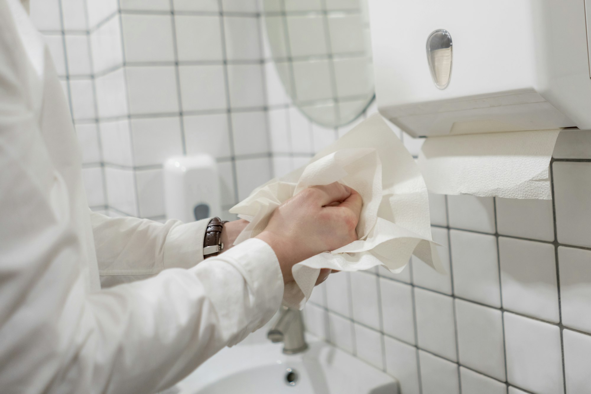 Washing hands with a paper towel in an office bathroom. Once used the paper towel will be put through Recorra's paper towel recycling process.