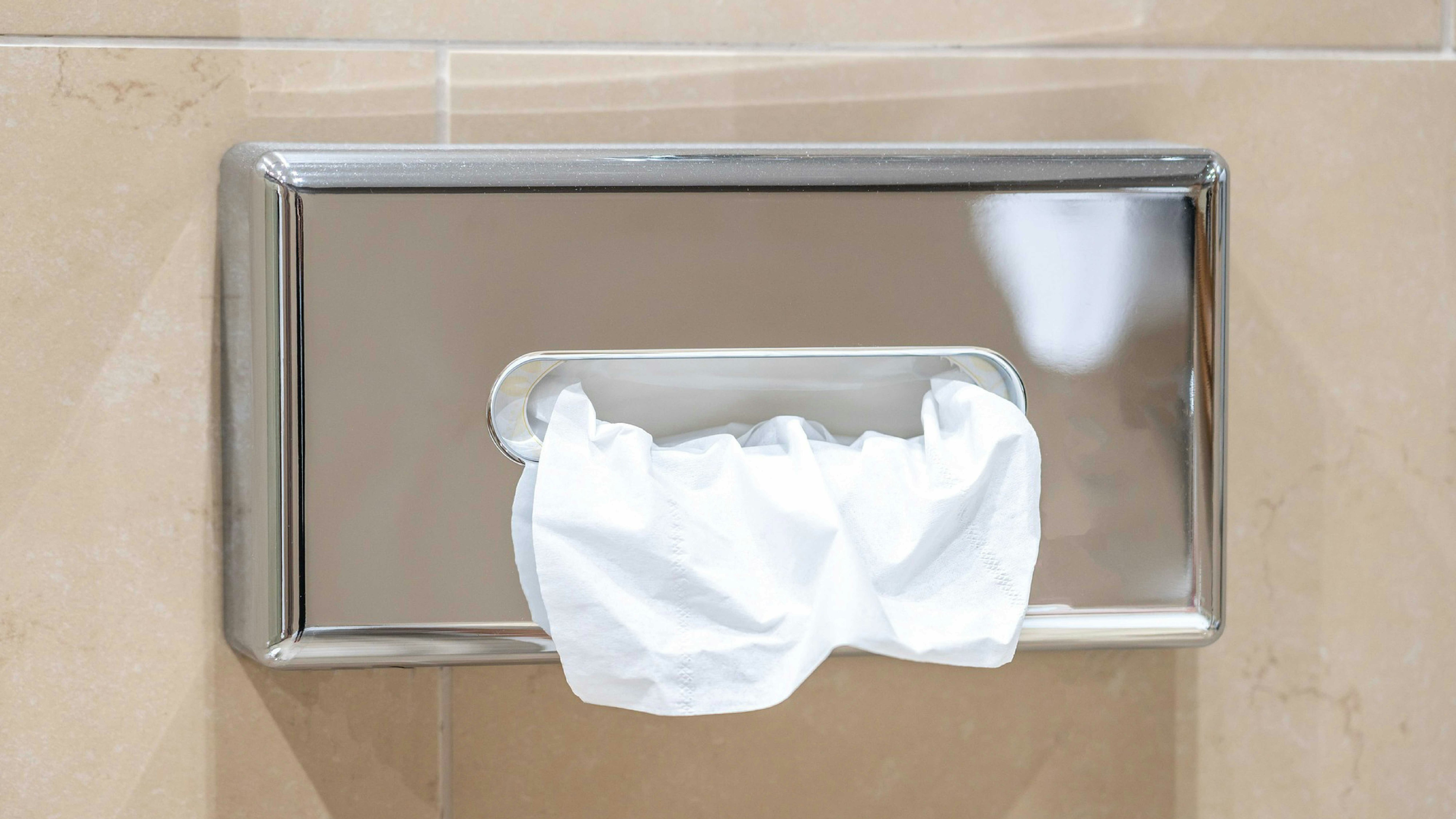 Silver Paper towel disposer on the wall of an office bathroom.